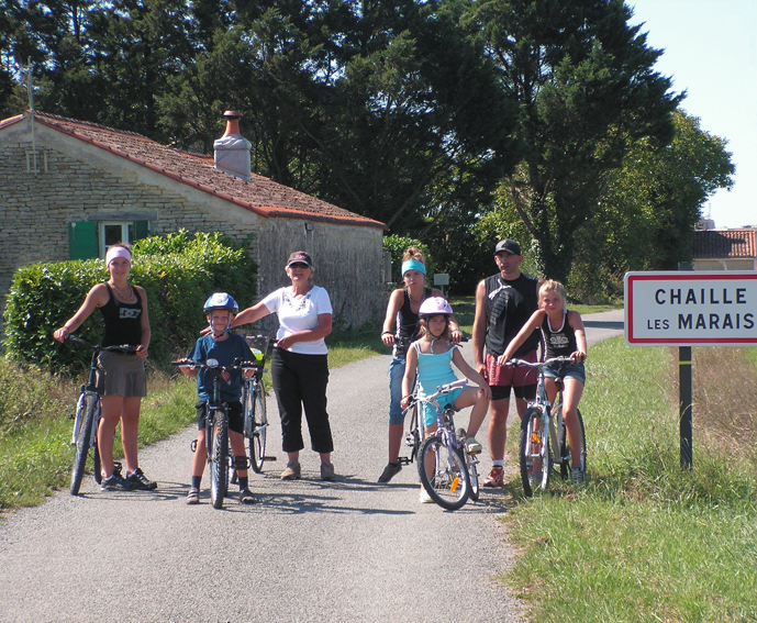Famille à vélo devant un panneau d’entrée de village