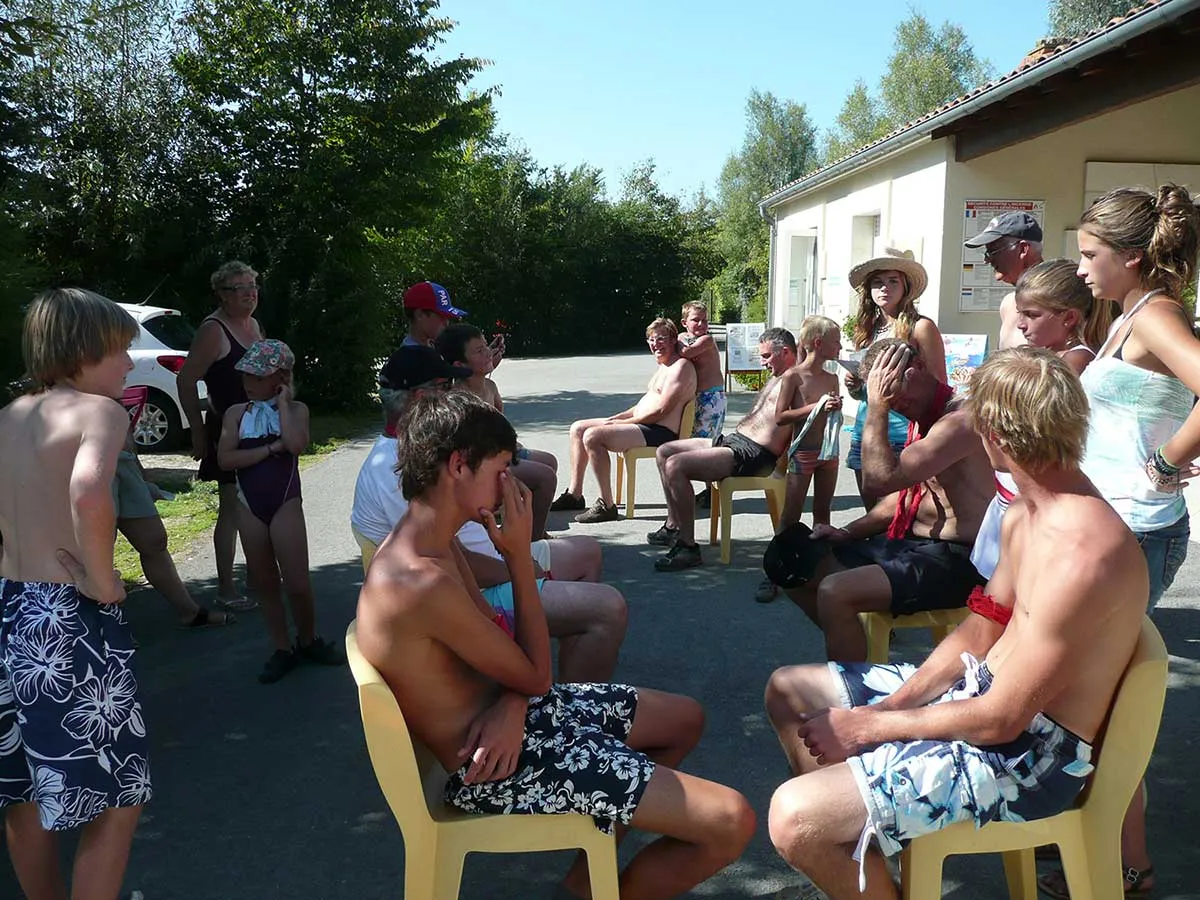Participants assis en cercle lors d’un jeu collectif en plein air au camping de l'ile cariot en Vendée